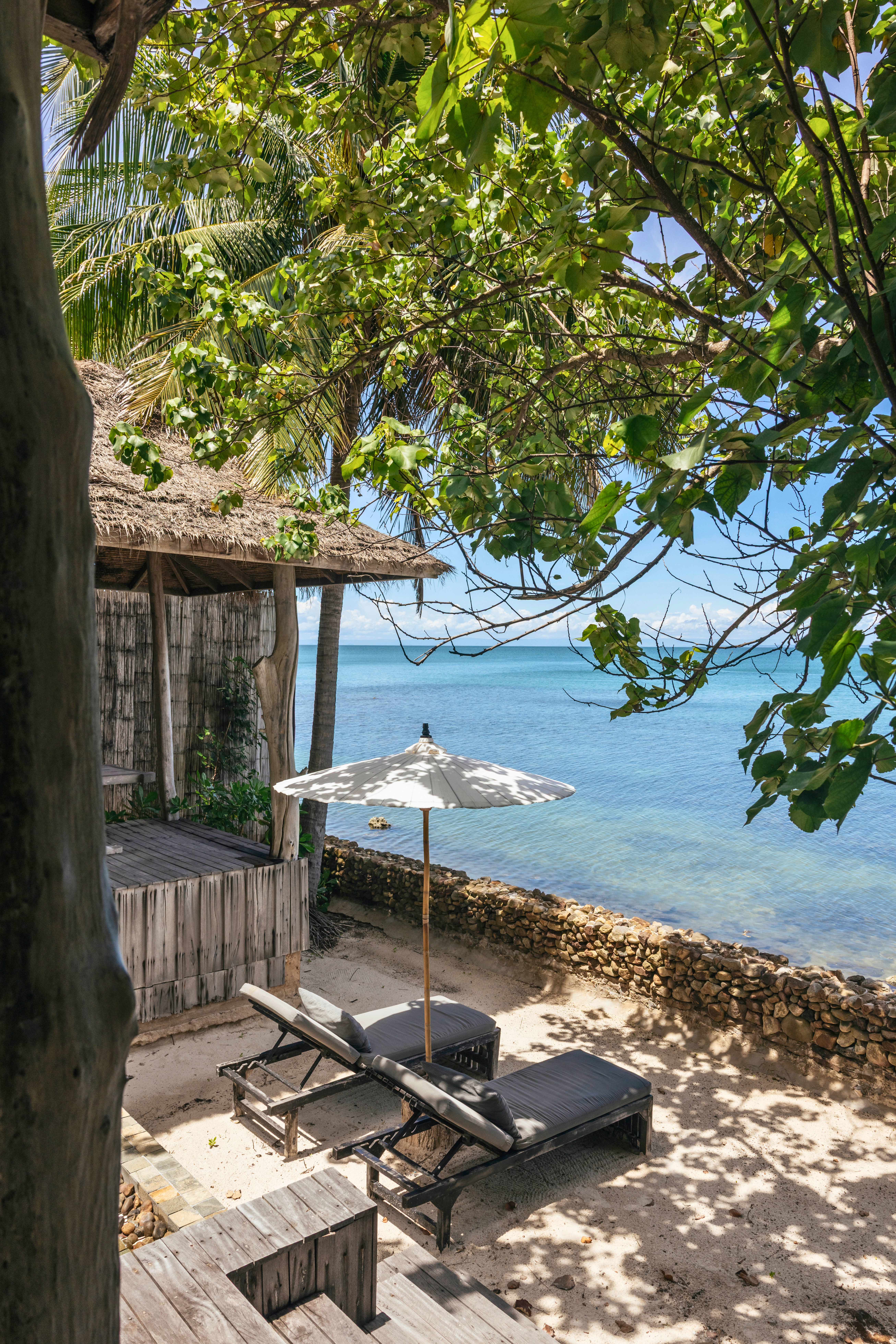 Beach resort with wooden deck, lounge chairs, and ocean view
